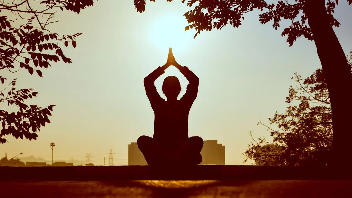 A person sitting outdoors at sunset practising a slow breathing exercise