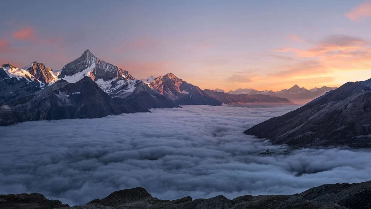 Mountain peaks rising above a layer of cloud at sunrise
