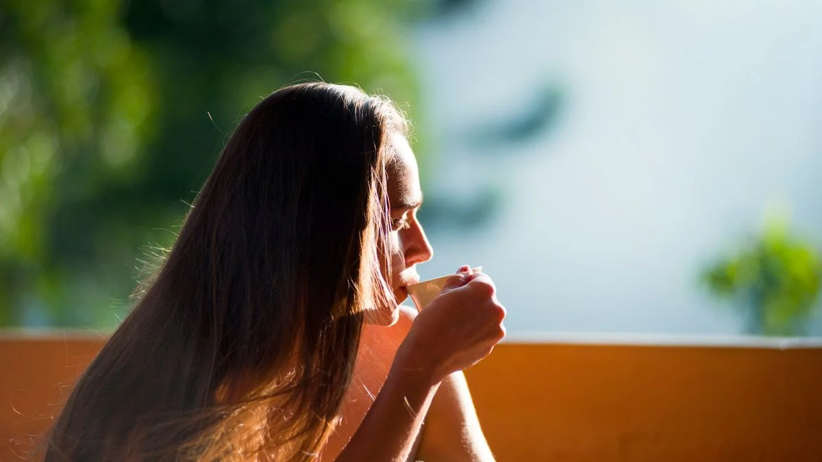 A person pausing over a warm drink in morning light before starting the day